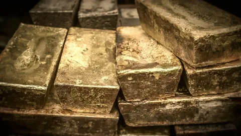 Close-up image showing stacked gold bars with a rustic metallic texture, representing wealth, investment value, and the global commodities market.