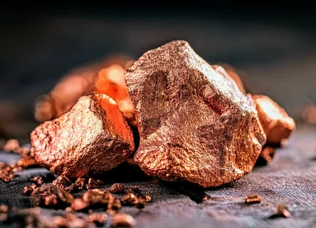 Close-up of shiny raw copper ore pieces with a metallic orange-brown texture, symbolizing industrial use, global demand, and the importance of copper in commodity trading.